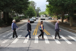 photo of four people walking in crosswalk, day