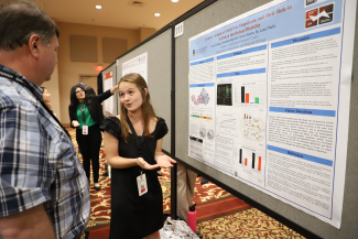 photo of people speaking in front of posters, ballroom