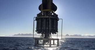 photo of scientific device suspended about sea, mountains and sky in background