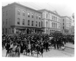 black and white photo of people in the street, with buildings