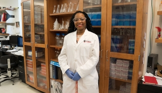 photo of woman in laboratory, in what lab coat with shelves and bottles