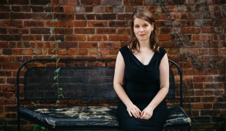 photo of woman sitting on a bench in front of brick wall