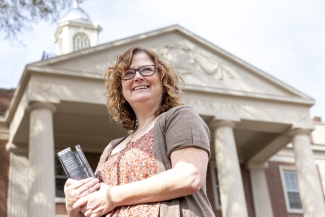 photo of woman holding books, with building, day