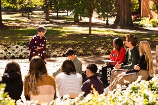 photo of professor and group of students outdoors, day