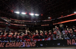 photo of marching band members in seats at stadium