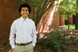 photo of man, next to brick wall and tree