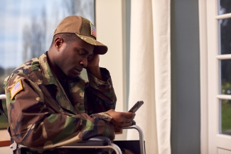 photo of man seated looking at cell phone