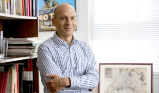 photo of man in office with framed map, books