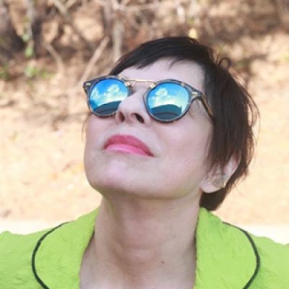 photo of woman looking up, with sunglasses reflecting sky