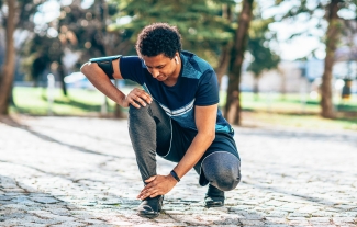 photo of runner kneeling to touch ankle