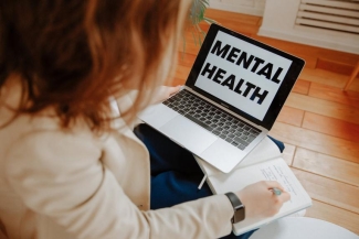 photo of person with laptop open, writing in a book