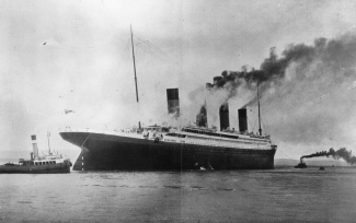 black and white photo of ship and tugs