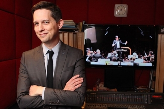 photo of man in sound booth with video screen