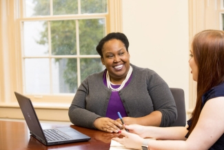 photo of two women at a table in a conference room, with window