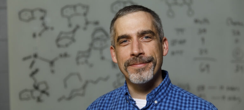 photo of man, chemical diagrams in background
