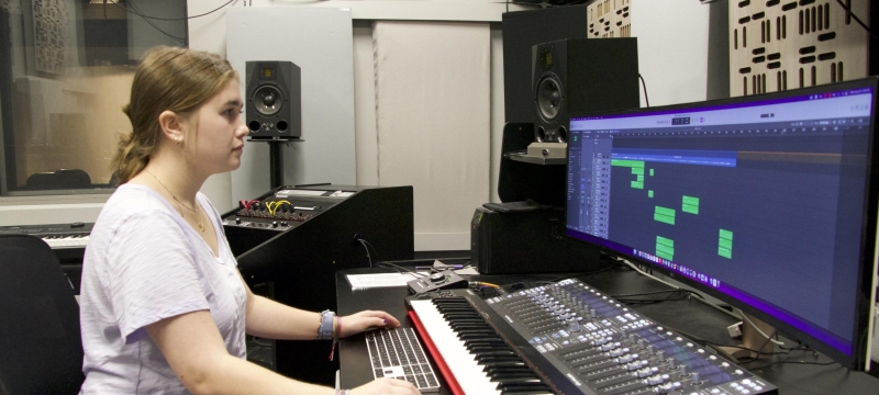 photo of student sitting at sound board with computer screen