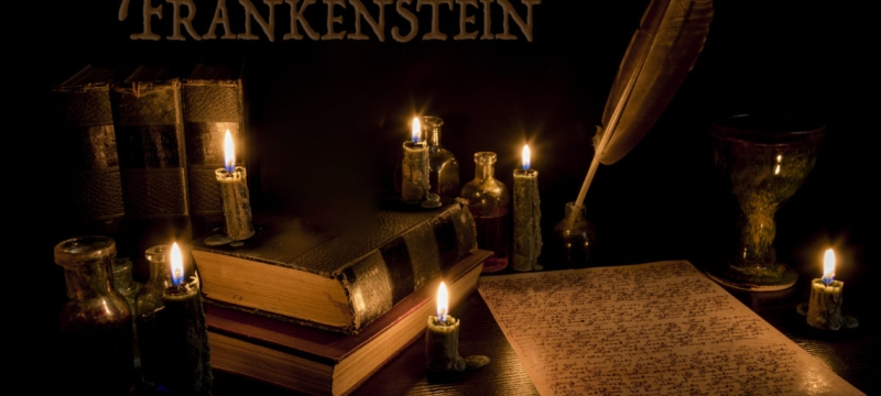 graphic with Frankenstein word, quill pen and paper, candles
