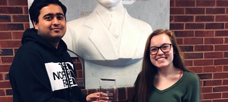 photo of two people with award and bust statue
