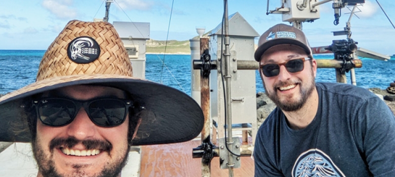 photo of two men, with instruments and sea in background