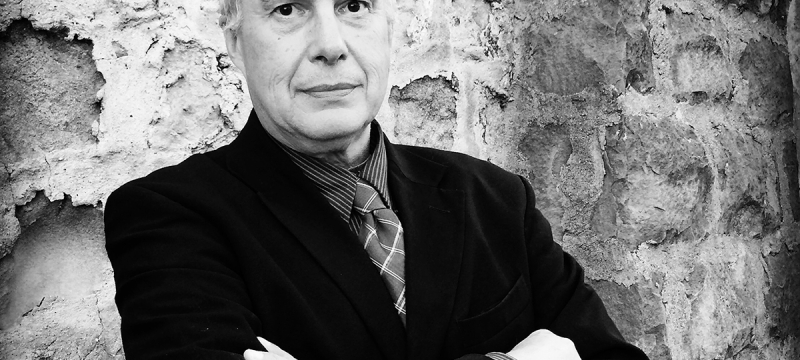 black and white photo of man, with stone wall