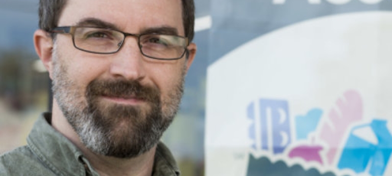 photo of man in front of sign in store window