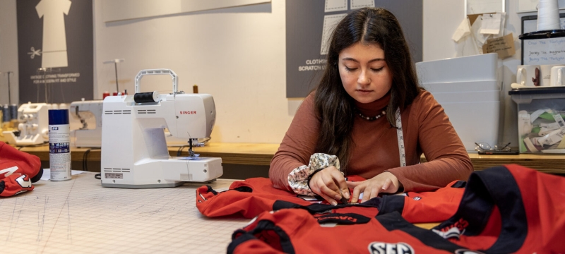 photo of woman sewing a red jersey