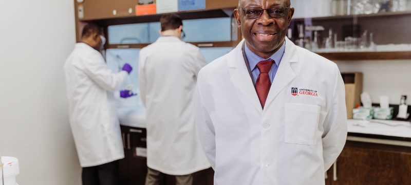 photo of man in lab coat, with two other men in background lab