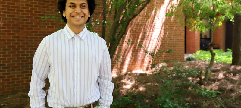 photo of man, next to brick wall and tree