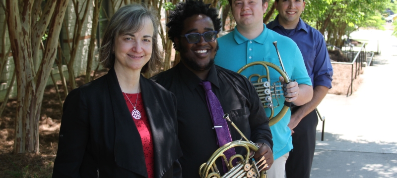 photo of four musicians, two holding horns