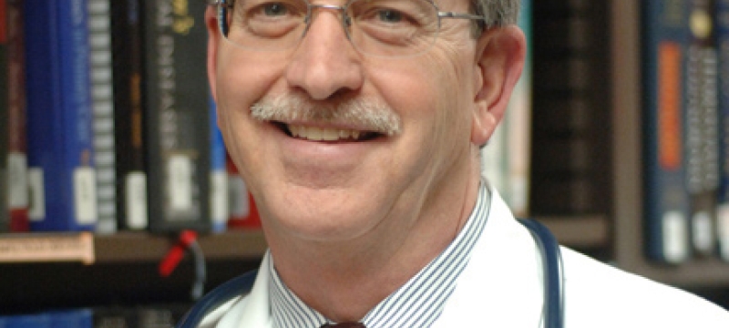 headshot of man, with books in background