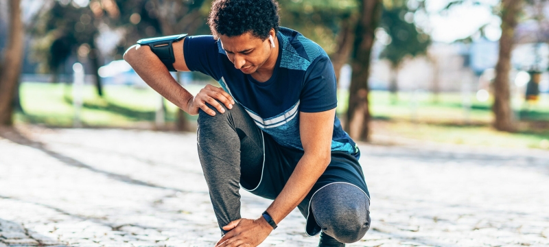 photo of runner kneeling to touch ankle