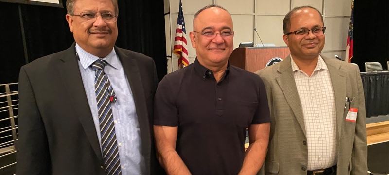 photo of three men, flag and podium in background