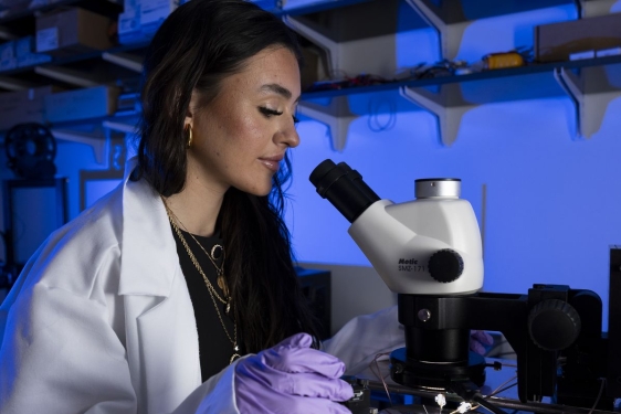photo ofo woman with microscope, lab coat, gloves