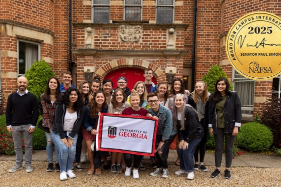 group photo of people in front of old brick building, holding flag