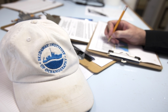 photo of hat and hand writing on clipboard, paper