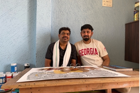 photo of two men, with drawing on table