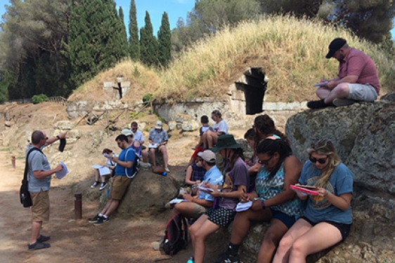 students with professor at ancient tomb opening