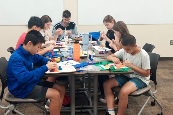 photo of 7 people at a table assembling materials