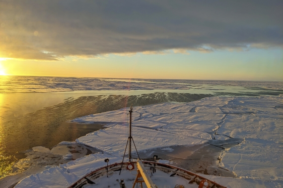 photo of sunrise over frozen sea, with bow of ship