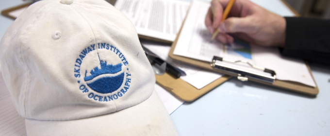 photo of hat and hand writing on clipboard, paper