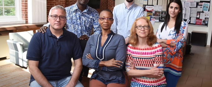 photo of six people, inside with brick wall