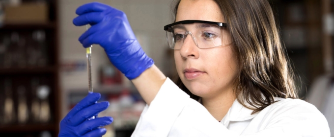 photo of woman with testable, blue gloves, lab coat