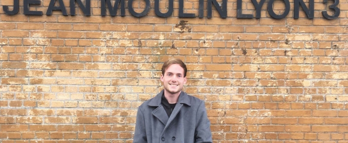 photo of man in front of wall with letters in black