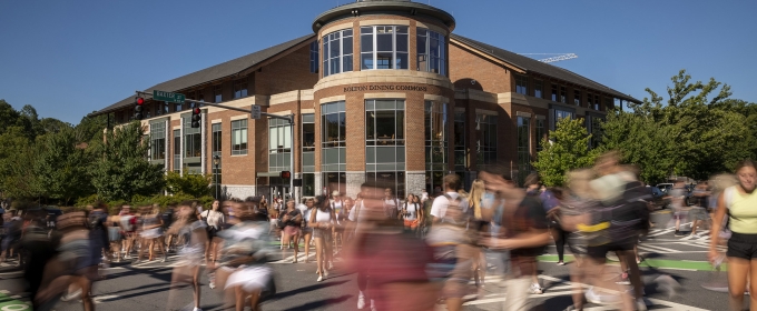 photo of blurred people crossing an intersection, with blue sky