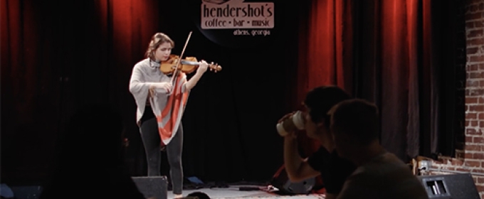 still photo of woman playing violin on a club stage