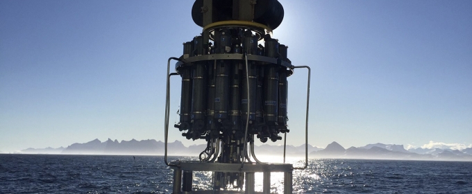 photo of scientific device suspended about sea, mountains and sky in background