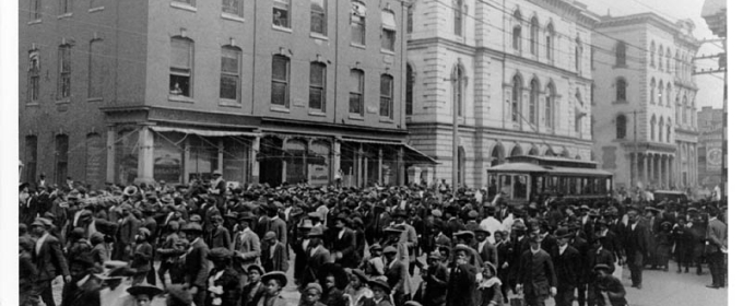 black and white photo of people in the street, with buildings