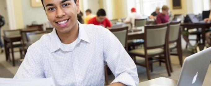 student in classroom with laptop and paper