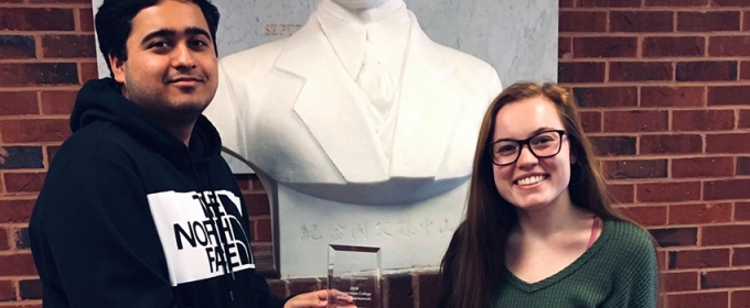 photo of two people with award and bust statue