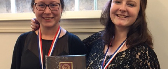 two women with plaque and medals